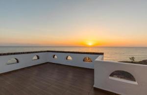 a sunset over the ocean from a house at Starlight Luxury Seaside Villa & Suites in Imerovigli