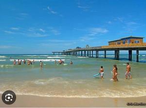 a group of people in the water at a beach with a pier at Canto dos pássaros in Tramandaí