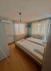 a bedroom with two beds and a wall with windows at E2 Residence in Balchik