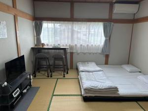 a room with two beds and a table and a tv at 富士山を眺められる宿 ゲストハウス花水木 in Nishikatsuracho