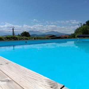 a large blue swimming pool with mountains in the background at Pyrenees Vue Gite - Owl - Vues Fantastique, Petit-Déjeuner, Calme, Piscine, Parking - Brand New in Saint-Gaudens