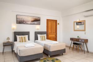 a hotel room with two beds and a desk at Dora Pool Studios by Konnect,150m from the Beach in Agios Georgios