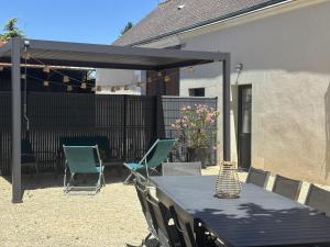 a patio with a table and chairs and a black canopy at Gîte La Patouille in Amboise