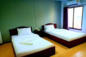two beds in a room with a window at House Number 3 in Phitsanulok