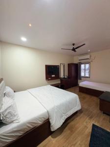 a bedroom with a white bed and a flat screen tv at TSR Grand Hotel in Bhogāpuram +21 photos