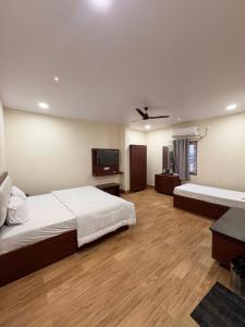 a bedroom with two beds and a flat screen tv at TSR Grand Hotel in Bhogāpuram
