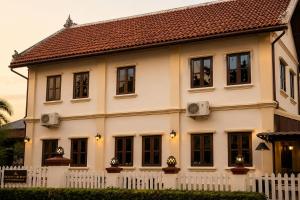 a large white house with a white fence at Luang Prabang Legend Hotel in Luang Prabang
