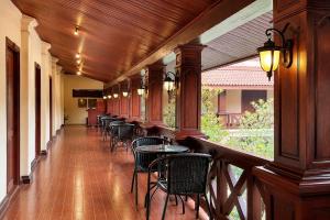 a porch with chairs and a table and a bar at Luang Prabang Legend Hotel in Luang Prabang