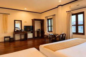 a bedroom with a bed and a desk and a television at Luang Prabang Legend Hotel in Luang Prabang