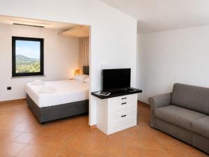 a bedroom with a bed and a couch and a television at Domo s'Altura in Porto Rotondo