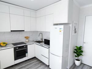 a white kitchen with white cabinets and a refrigerator at Grand Angleterre Penthouse in Astana
