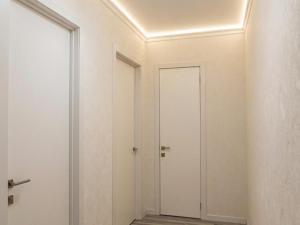 a corridor with white walls and a door at Grand Angleterre Penthouse in Astana