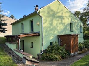 a green house with a building with a garage at Ferienhaus Schwope 04654 Frohburg OT Kohren-Sahlis Friedensstraße 33 in Kohren-Sahlis