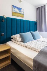 a bed with a blue headboard in a bedroom at Willa Mak in Krynica Zdrój