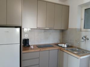 a kitchen with white cabinets and a sink and a refrigerator at Bel Air Rooms in Himare