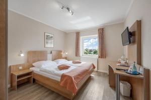 a bedroom with a bed and a desk and a television at Haags Hotel Niedersachsenhof in Verden
