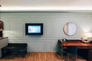 a room with a desk and a television on a wall at The Craft Nimman in Chiang Mai