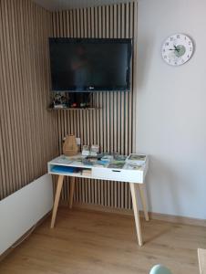 a table with a tv on a wall with a clock at Les Reflets de Meuse in Revin