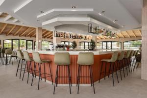 a bar with a row of stools in a restaurant at Wyndham Mallorca Portocolom Resort in Portocolom