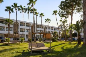 a hotel with palm trees in front of it at Wyndham Mallorca Portocolom Resort in Portocolom
