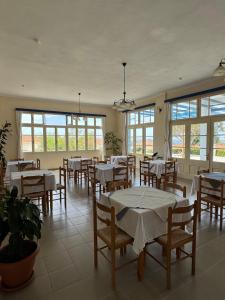 a dining room with tables and chairs and windows at Orama Hotel in Sígrion