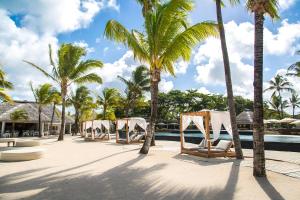 eine Reihe von Stühlen und Palmen neben einem Pool in der Unterkunft Anahita Golf & Spa Resort in Beau Champ