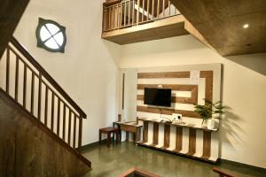 a living room with a television on a wall at Gavadana Resort Coorg in Madikeri
