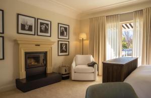a hotel room with a bed and a chair and a fireplace at Maison Cabrière Boutique Hotel in Franschhoek