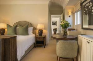 a bedroom with a bed and a table and a desk at Maison Cabrière Boutique Hotel in Franschhoek