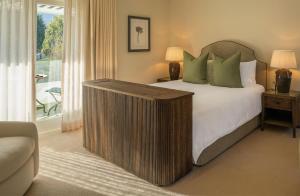 a bedroom with a large bed and a balcony at Maison Cabrière Boutique Hotel in Franschhoek