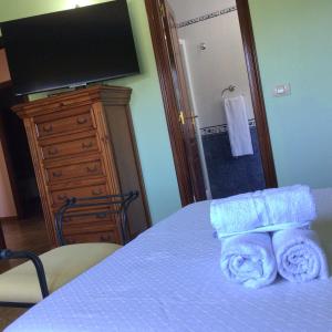 a bedroom with a bed with towels and a television at HYP - Aranza Descanso Natural in Sotomayor