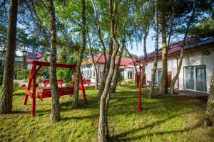 a red swing in a yard next to a house at Las i Morze - Dźwirzyno in Dźwirzyno