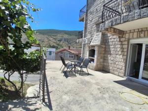 eine Terrasse mit Tisch und Stühlen an einem Gebäude in der Unterkunft Radoš in Igalo