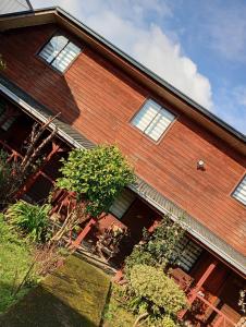 a brick house with windows and bushes in front of it at Hostal y Cabañas Guaje in Valdivia