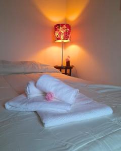 a bed with white towels and a pink flower on it at Temporario La Marcela in Resistencia