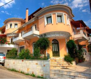 ein großes orangefarbenes Haus mit einem Balkon an einer Straße in der Unterkunft Ilian House in Parga