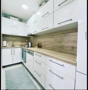 a kitchen with white cabinets and a wooden wall at Apartman Ika in Belgrade