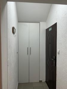 a hallway with two white cabinets and a black door at Apartman Ika in Belgrade