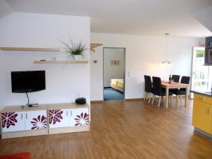 ein Wohnzimmer mit einem TV und einem Tisch mit Stühlen in der Unterkunft Backhaus Meeresblick in Meeschendorf