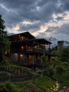 a house on a hill with mountains in the background at Villa Dabderr Mestia in Mestia