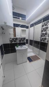 a white bathroom with a shower and a sink at La Flower Nesvady in Nesvady