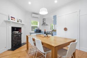 a dining room with a wooden table and white chairs at Coastal Cottage Retreat in Barwon Heads