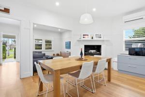 a dining room and living room with a wooden table and chairs at Coastal Cottage Retreat in Barwon Heads