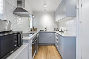 a kitchen with white cabinets and a black appliance at Coastal Cottage Retreat in Barwon Heads