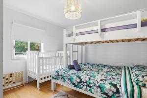 a white bedroom with a bunk bed and a crib at Coastal Cottage Retreat in Barwon Heads +9 photos