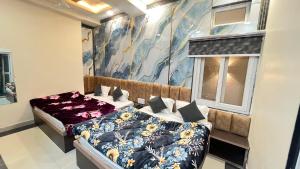 a bedroom with two beds and a painting on the wall at Hotel Kaka Inn in Ajmer