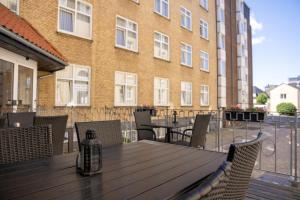 ein Holztisch und Stühle auf einem Balkon mit einem Gebäude in der Unterkunft Hotel Phønix Aalborg in Aalborg