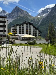 a building in the middle of a field with mountains at Rothornblick in Arosa