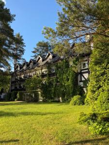 a large building on a lawn with trees at Kanu Club - ośrodek wypoczynkowy in Nowy Zyzdrój