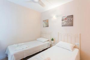 two beds in a room with white walls at Apartamento EntreOlas in El Verger +29 photos